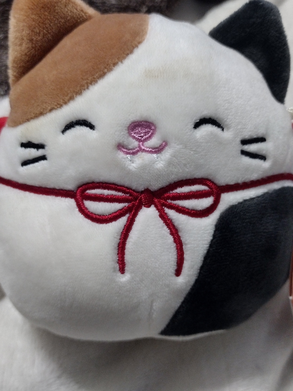 Squishmallows Calico Cat Plush in White, Brown, Black & Red Bow
